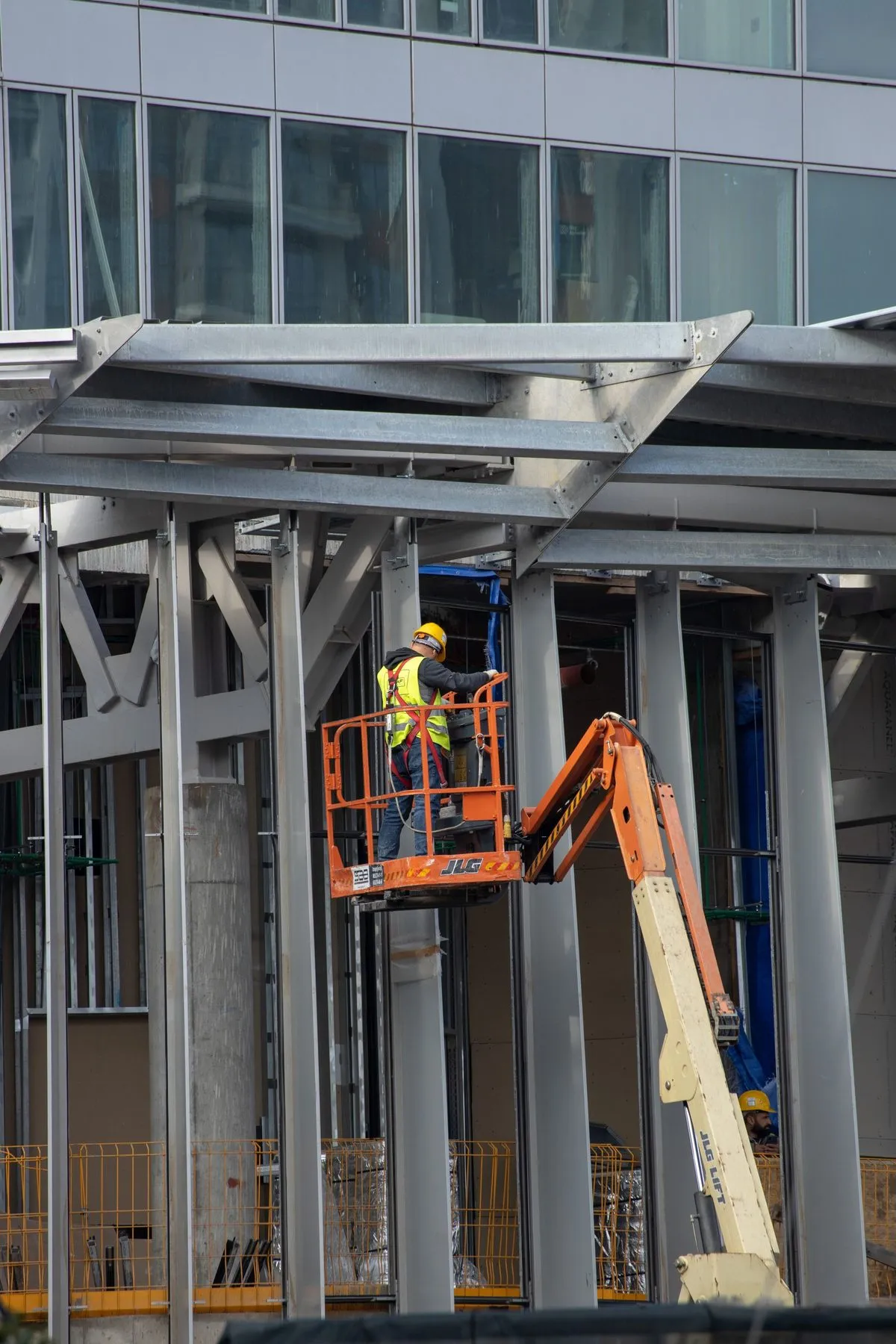 Opérateur en nacelle travaillant sur une structure métallique de bâtiment.