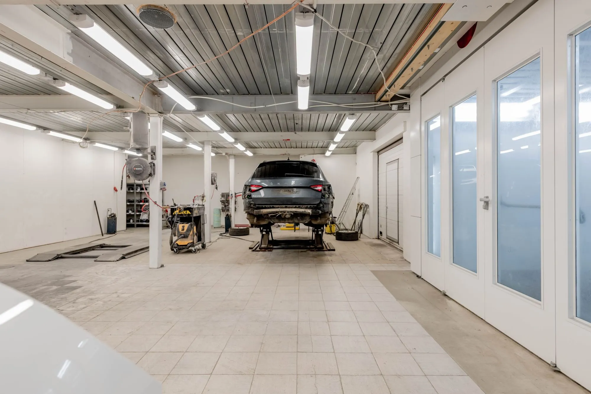 Atelier de réparation automobile clair, véhicule sur pont élévateur.